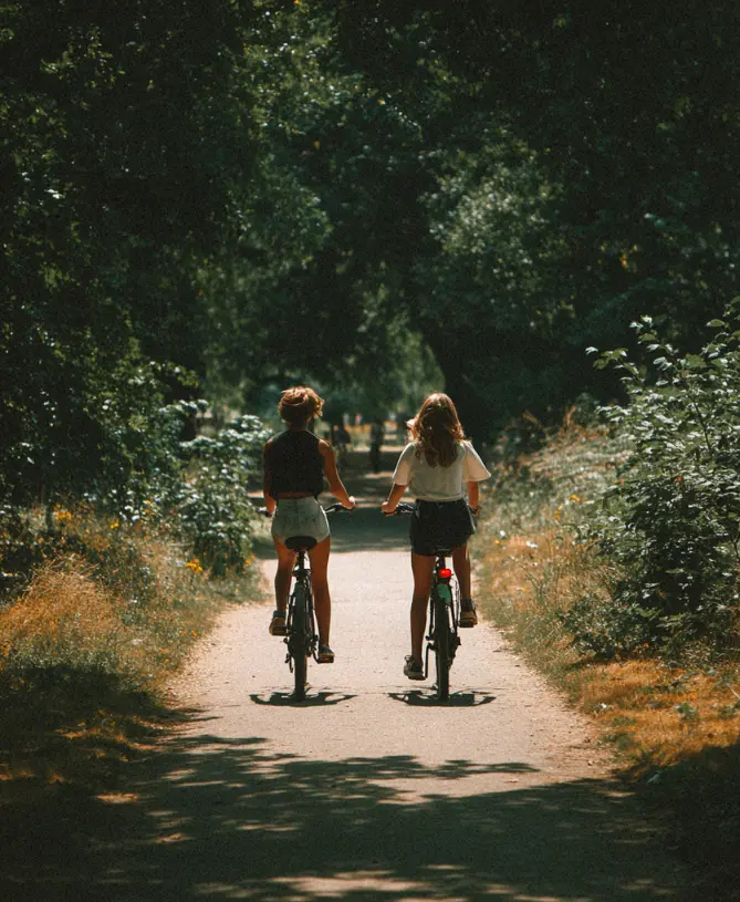 Two teenagers cycling through a London park in a residential group support programme